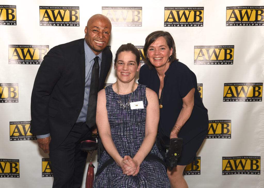 Sponsors posing for a photo with an AWB member, in front of an AWB backdrop.